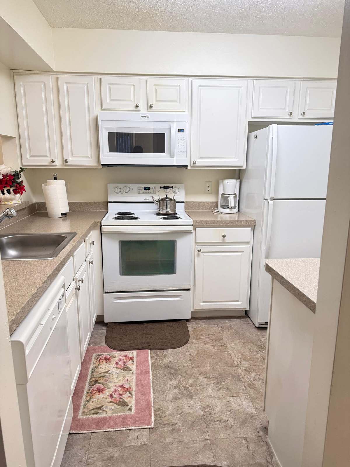 The kitchen, with white cabinets, a full-size cooker, microwave, dishwasher and refrigerator.