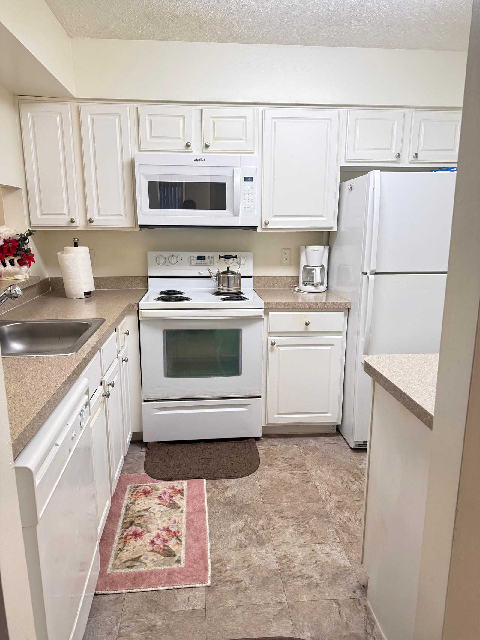 The kitchen, with white cabinets, a full-size cooker, microwave, dishwasher and refrigerator.