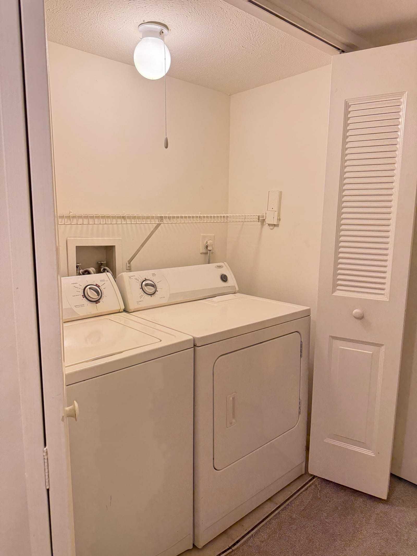 The in-unit laundry cupboard, with a full-size washing machine and tumble dryer side by side behind louvred doors.