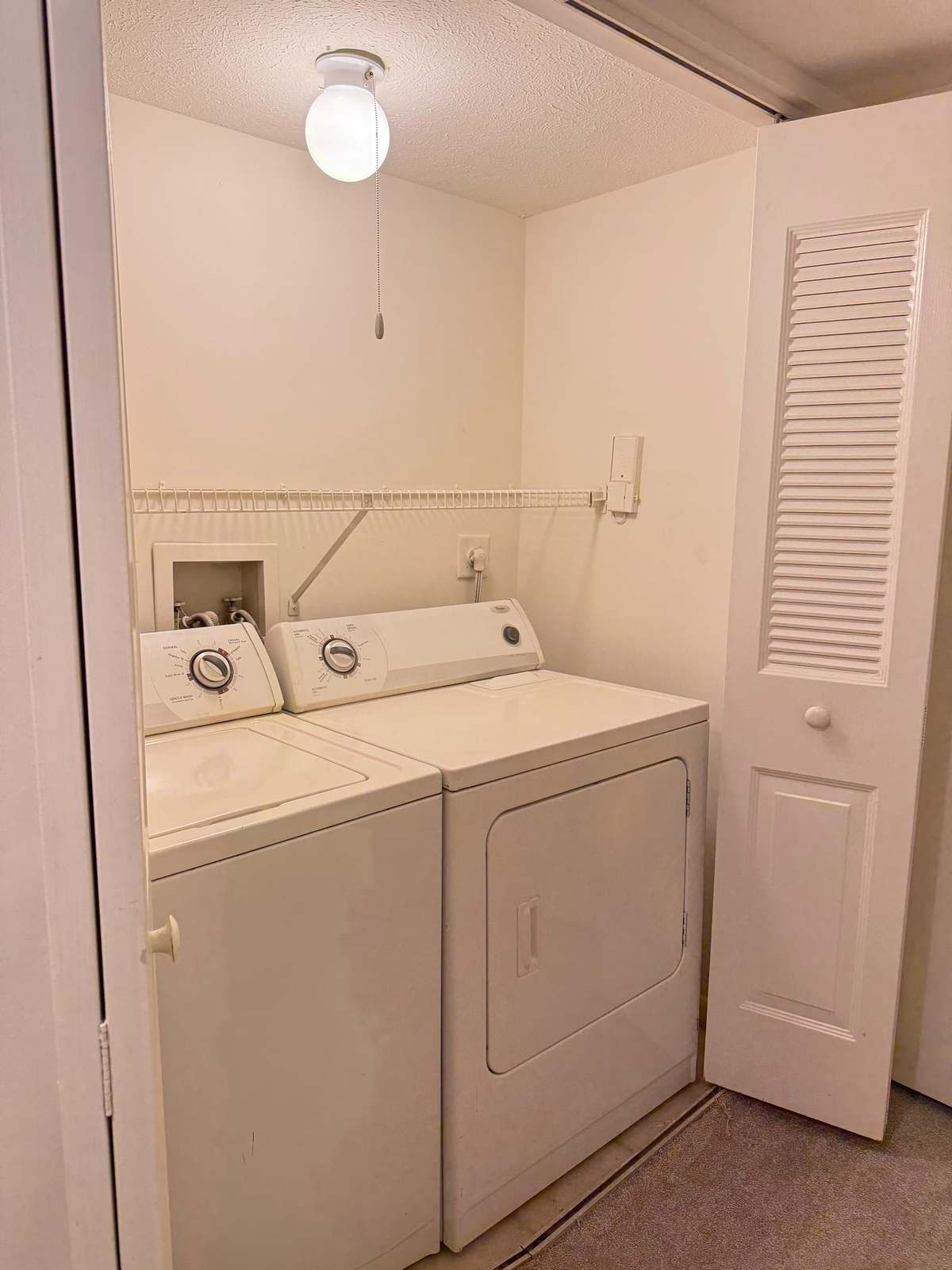 The in-unit laundry cupboard, with a full-size washing machine and tumble dryer side by side behind louvred doors.